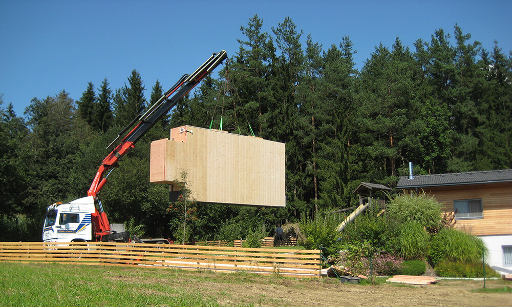 Kran hebt Holc Naturpool im Ganzen in die Baugrube